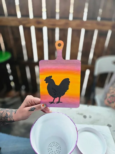 A painted rooster design and flower pot
