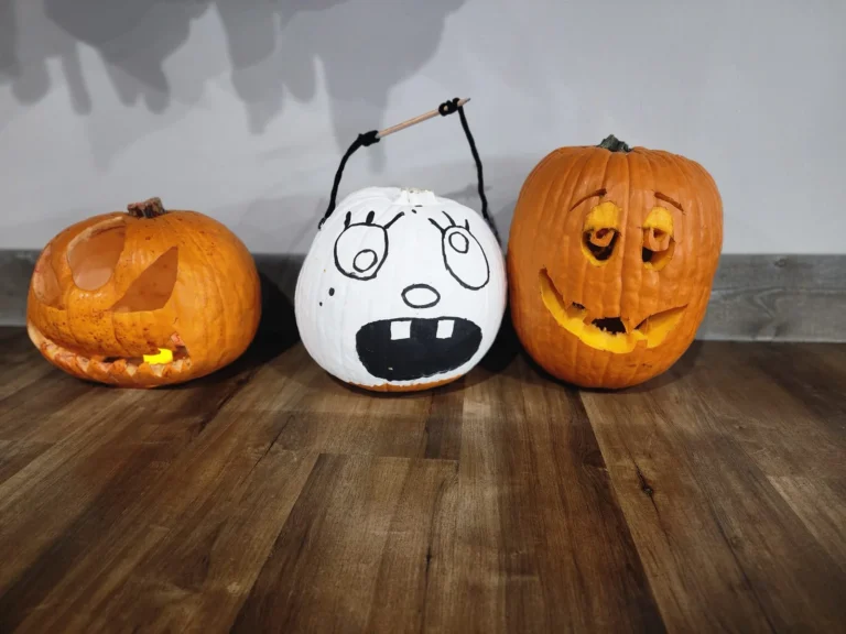Three carved pumpkins displayed on a wooden shelf.