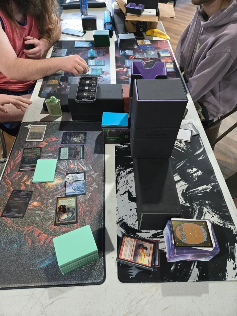 Players arrange Magic: The Gathering cards on a game table.