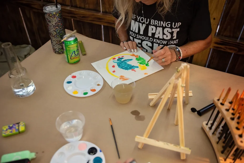 Participant holds up a colorful finished painting.