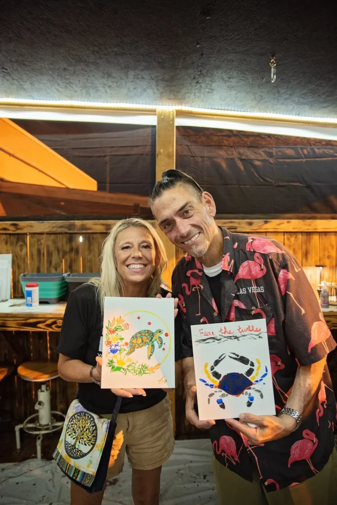 Two participants display their finished paintings.