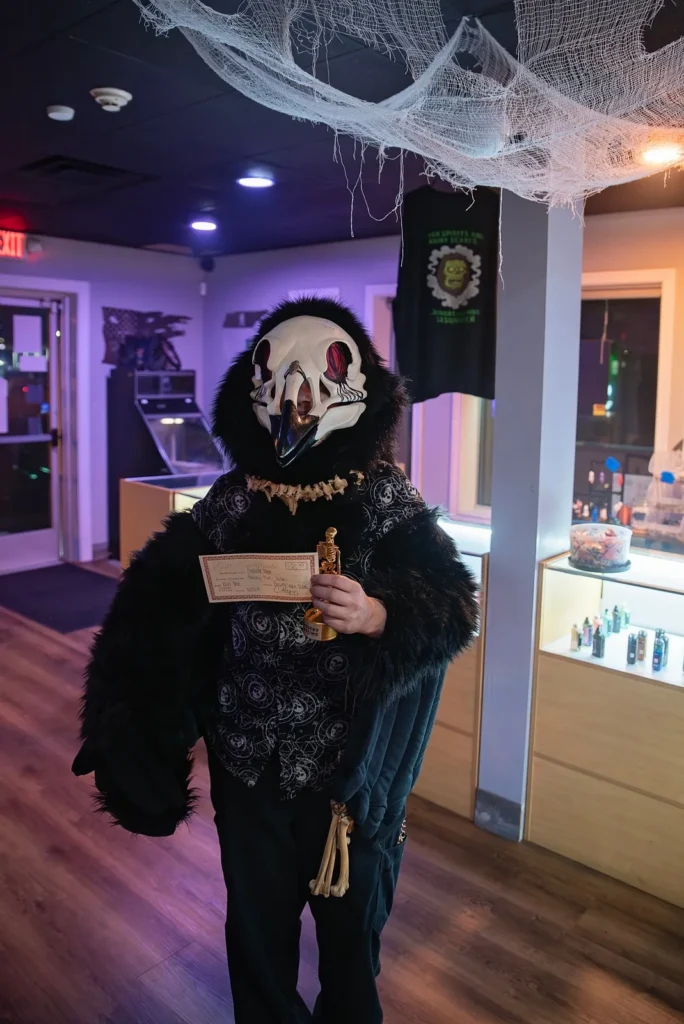 A masked Halloween-costumed guest poses inside the decorated store.